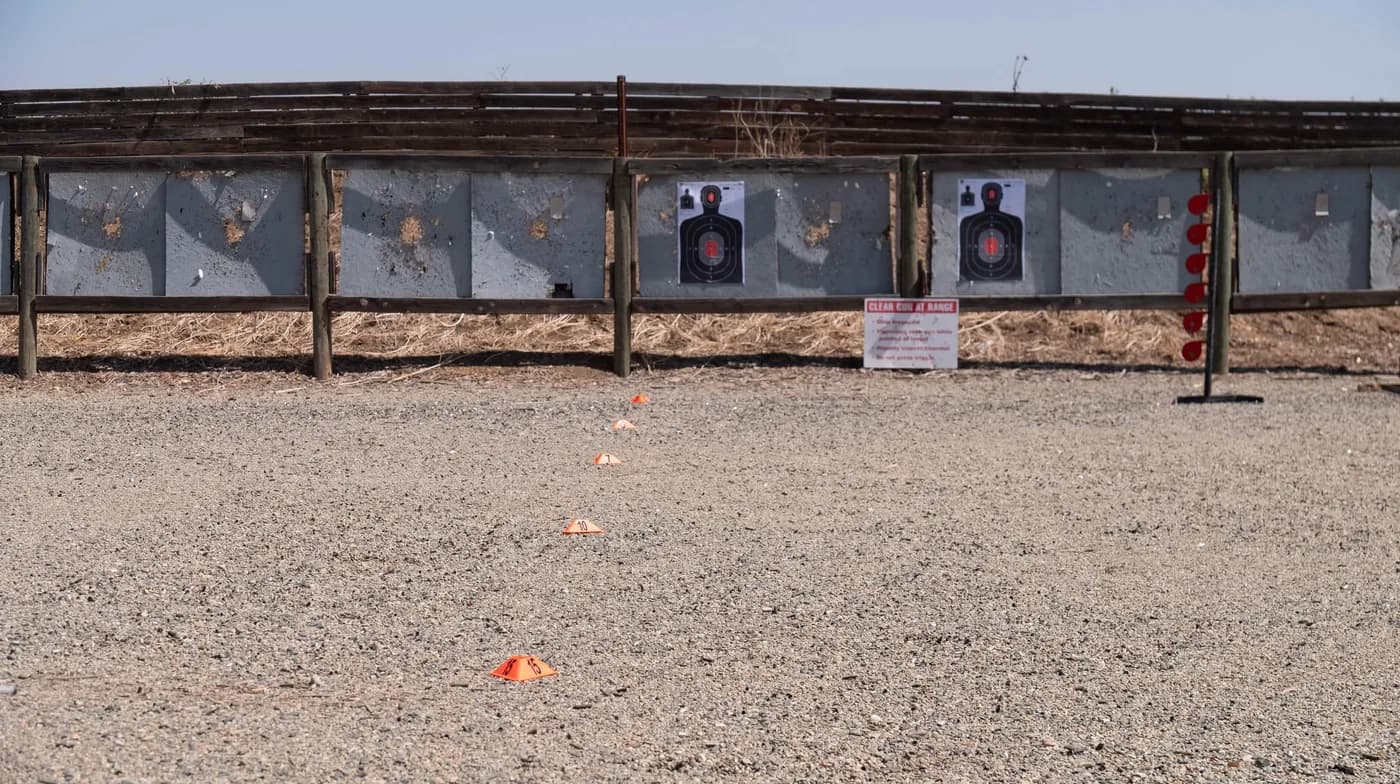The empty firing line at Exeter Gunslingers: silhouette targets on steel backers, and a row of numbered orange cones on the gravel marking the 15, 10 and 7 yard lines and the two shorter distances beyond.
